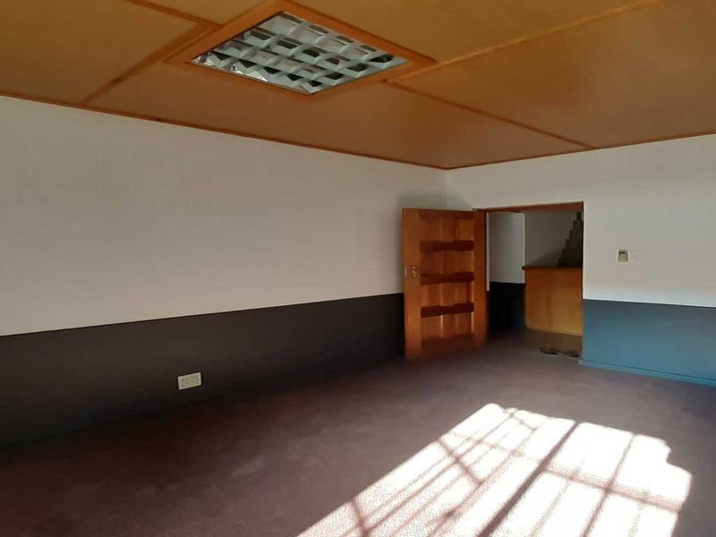 An empty office space featuring a glass block accent wall, recessed ceiling lighting, and a wooden door, ready for professional customization.