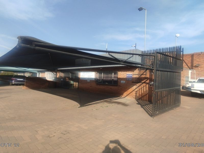 Front exterior view of the office property featuring a brick facade, security gate, and covered parking area.