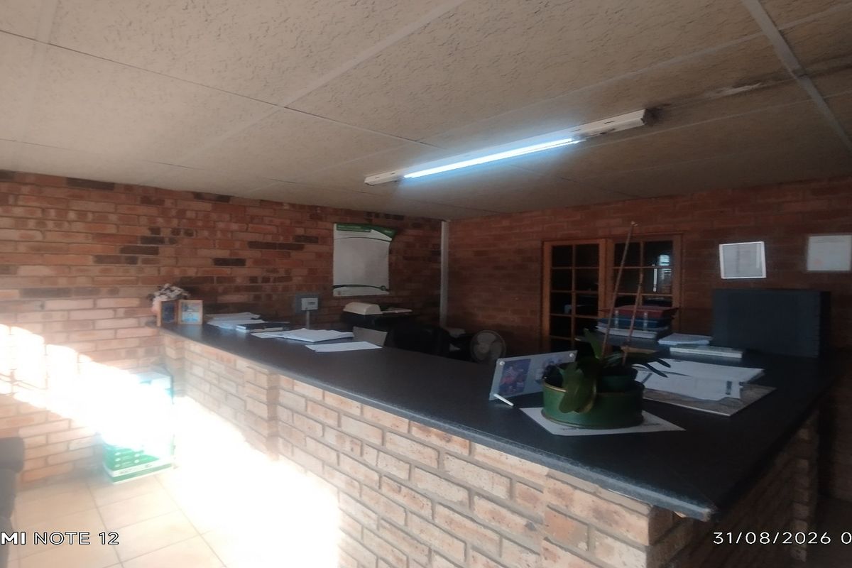Office reception area featuring a built-in brick counter, exposed brick walls, and functional fluorescent lighting.