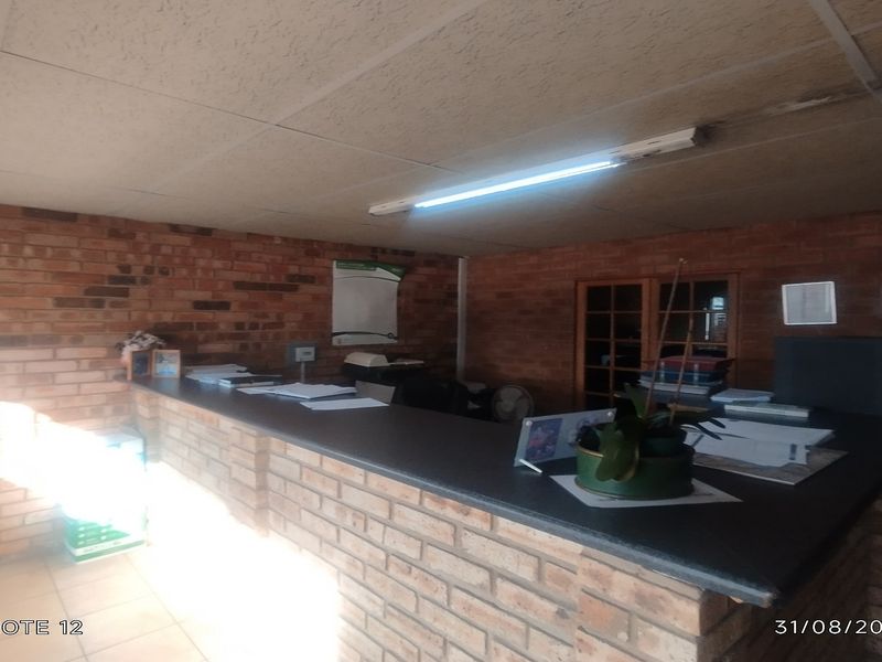 Office reception area featuring a built-in brick counter, exposed brick walls, and functional fluorescent lighting.