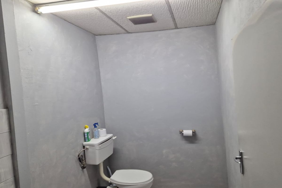 A functional commercial restroom featuring a standard toilet, drop ceiling, and basic wall finishes.