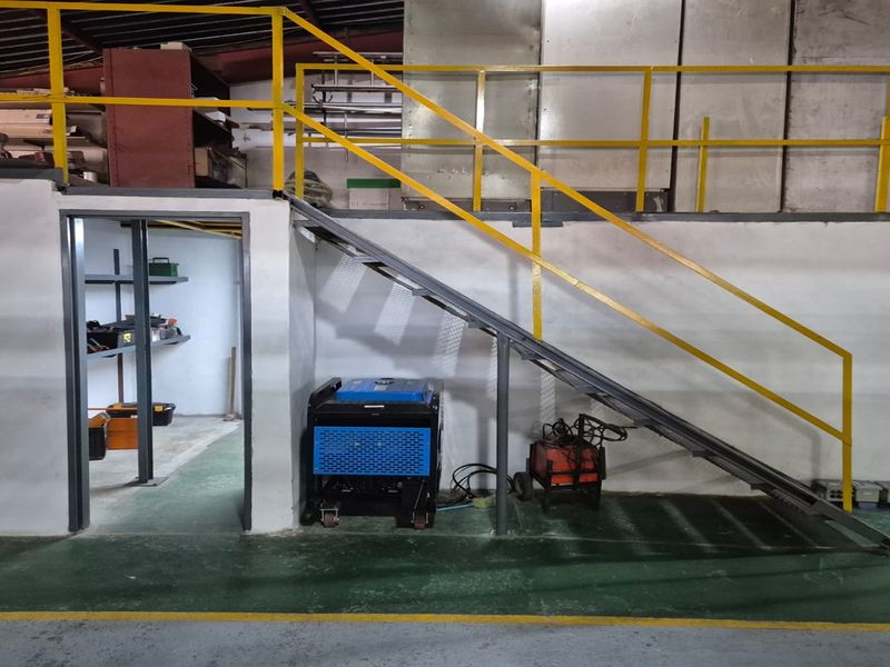 Commercial utility space featuring a metal staircase with safety railing leading to a mezzanine level, finished with durable epoxy flooring.