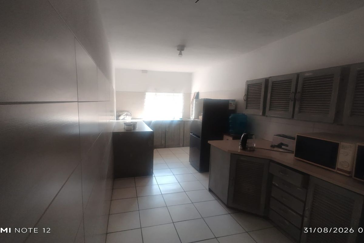 A functional kitchen space featuring tiled flooring, built-in cabinetry, and tiled wall finishes, currently requiring cosmetic updates to improve aesthetic appeal.