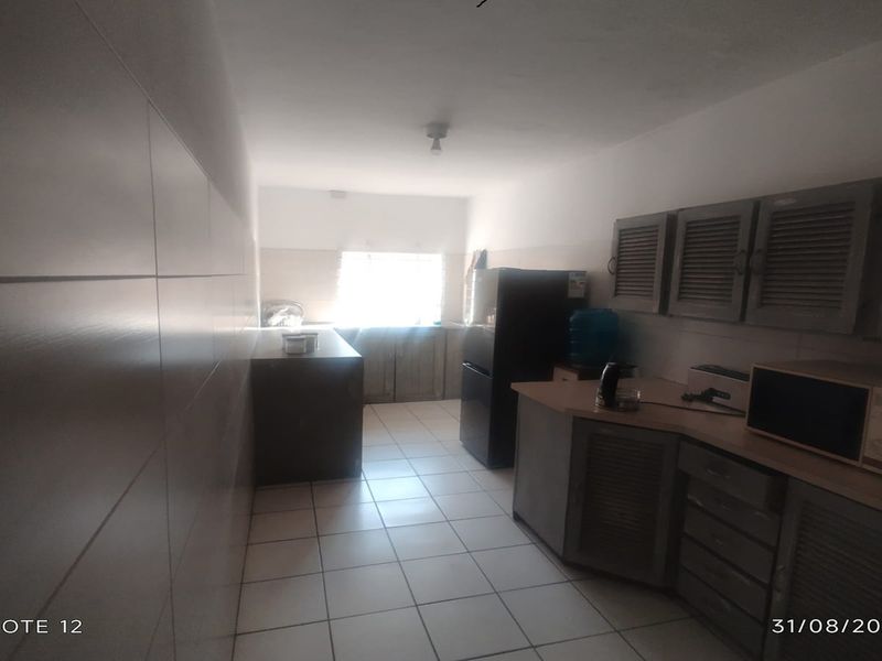 A functional kitchen space featuring tiled flooring, built-in cabinetry, and tiled wall finishes, currently requiring cosmetic updates to improve aesthetic appeal.