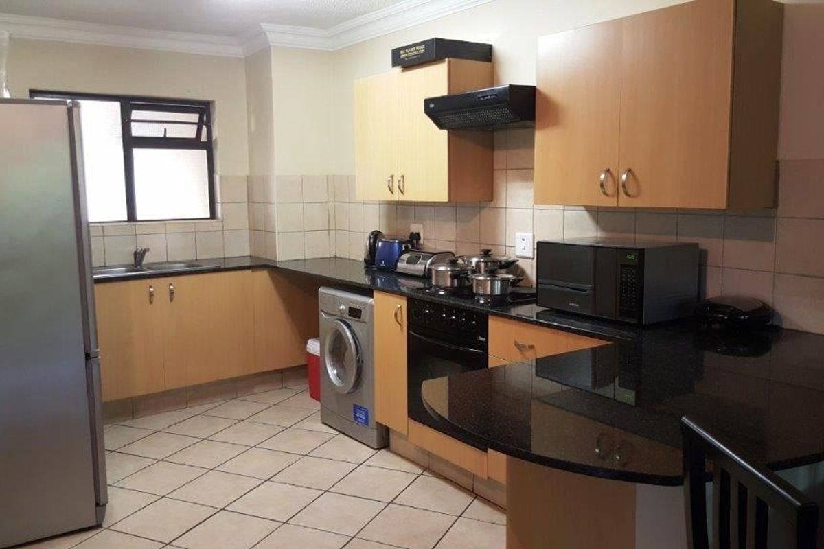 Functional kitchen featuring laminate cabinetry, granite countertops, tiled backsplash, and integrated appliances, offering a practical layout for daily cooking and preparation.