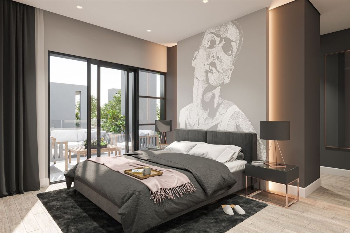 Modern bedroom featuring timber flooring, recessed lighting, and large sliding glass doors opening onto a private balcony.