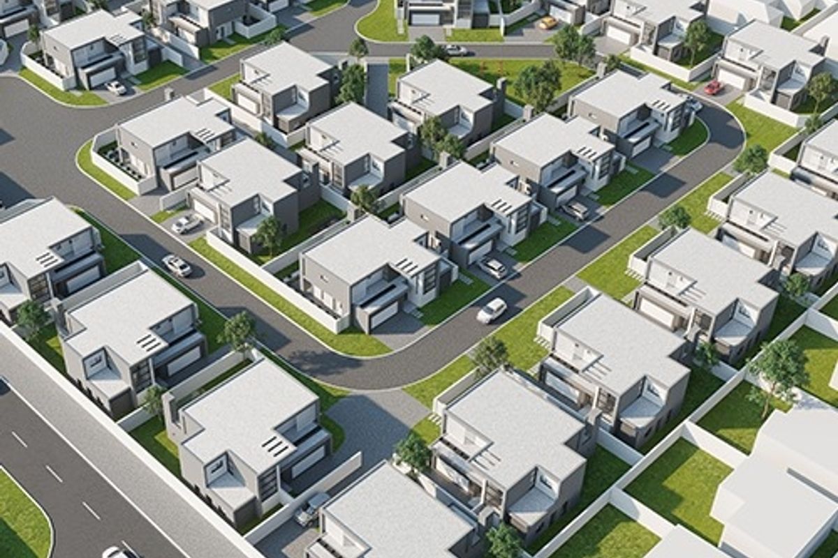 An aerial view of a modern residential housing estate featuring uniform architectural designs, paved streets, and landscaped plots.