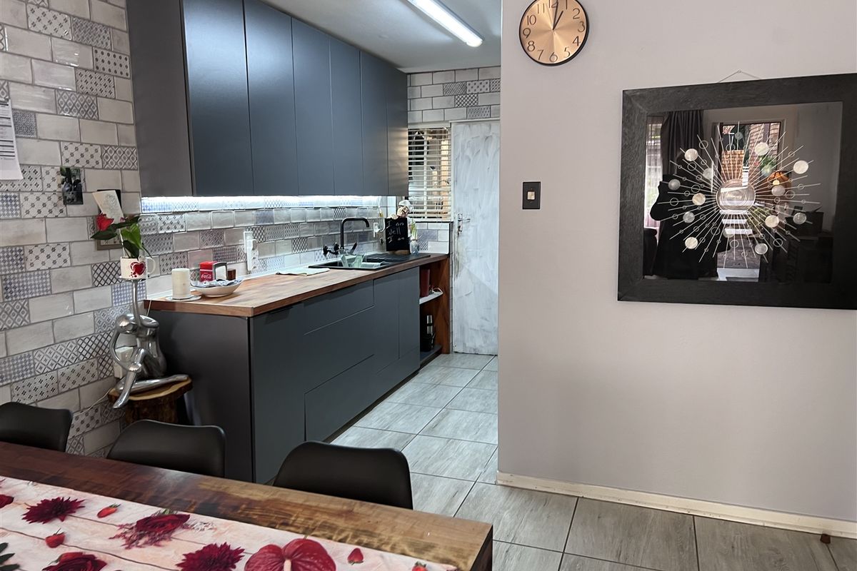 Modern kitchen featuring dark matte cabinetry, wooden countertops, and a decorative tiled backsplash, creating a contemporary and functional culinary space.