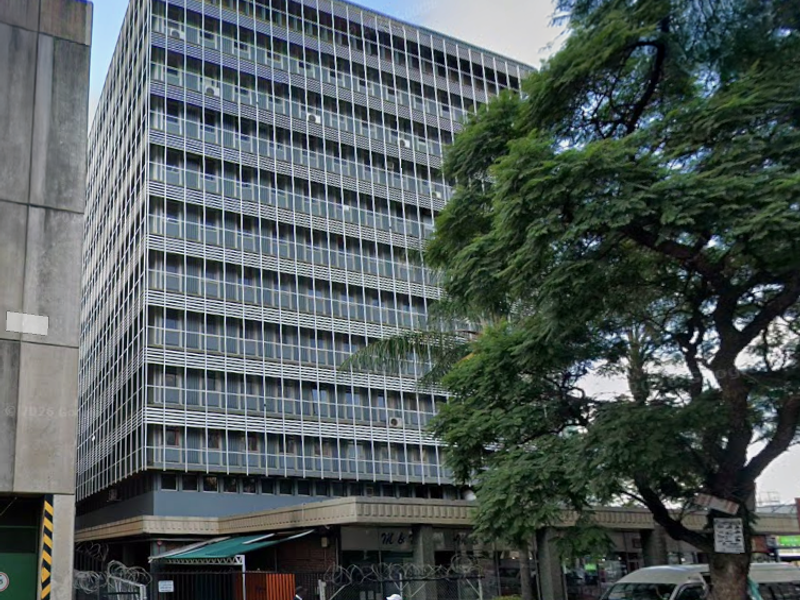 A multi-story commercial office building featuring a grid-patterned facade with integrated sun louvers and ground-level retail space.