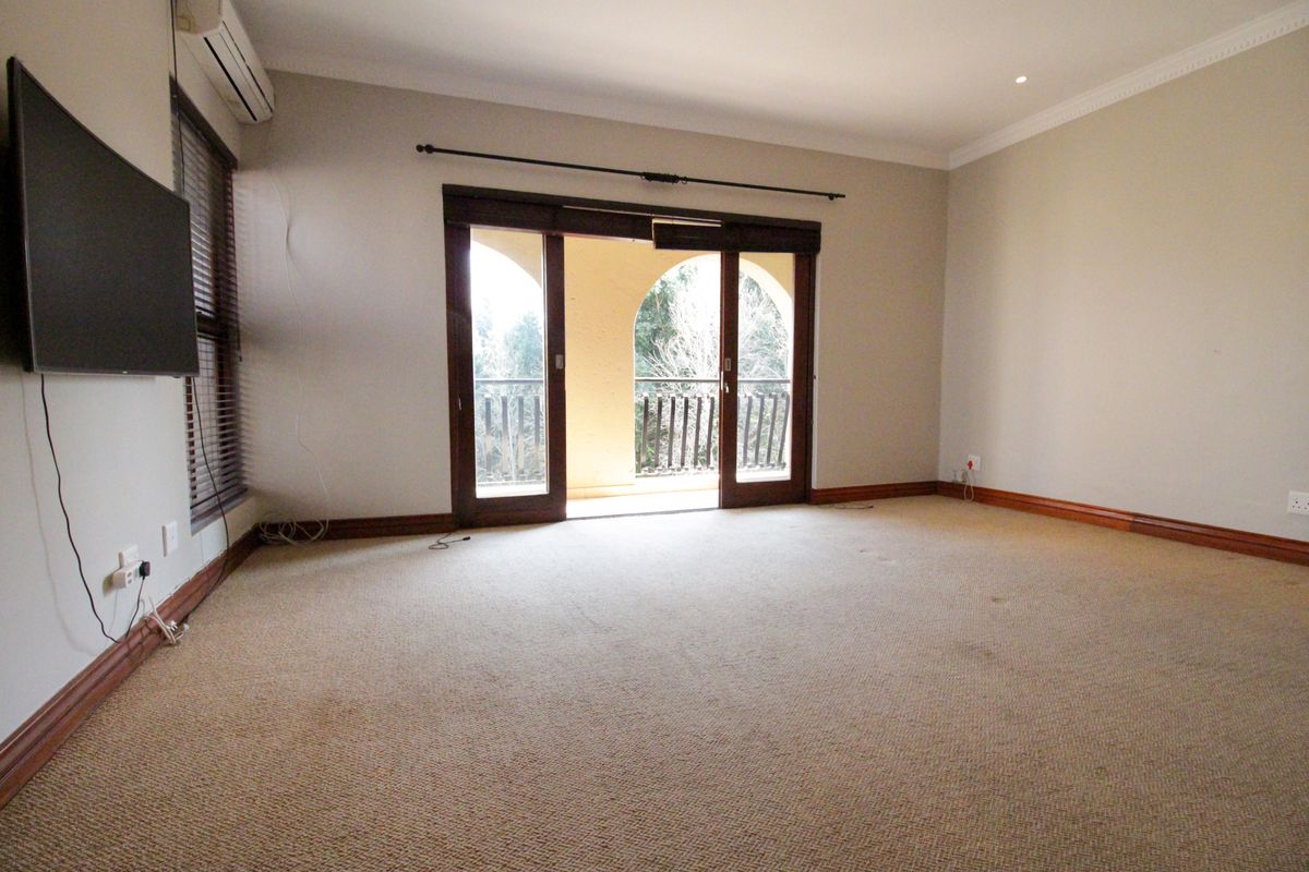 Spacious bedroom featuring neutral walls, carpet flooring, and sliding glass doors providing direct access to a private balcony.