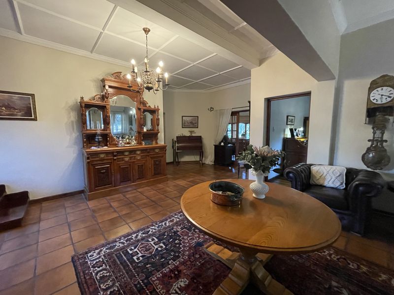 Spacious living area featuring traditional terracotta floor tiles, a classic coffered ceiling, and a central chandelier, offering a warm and character-filled atmosphere.