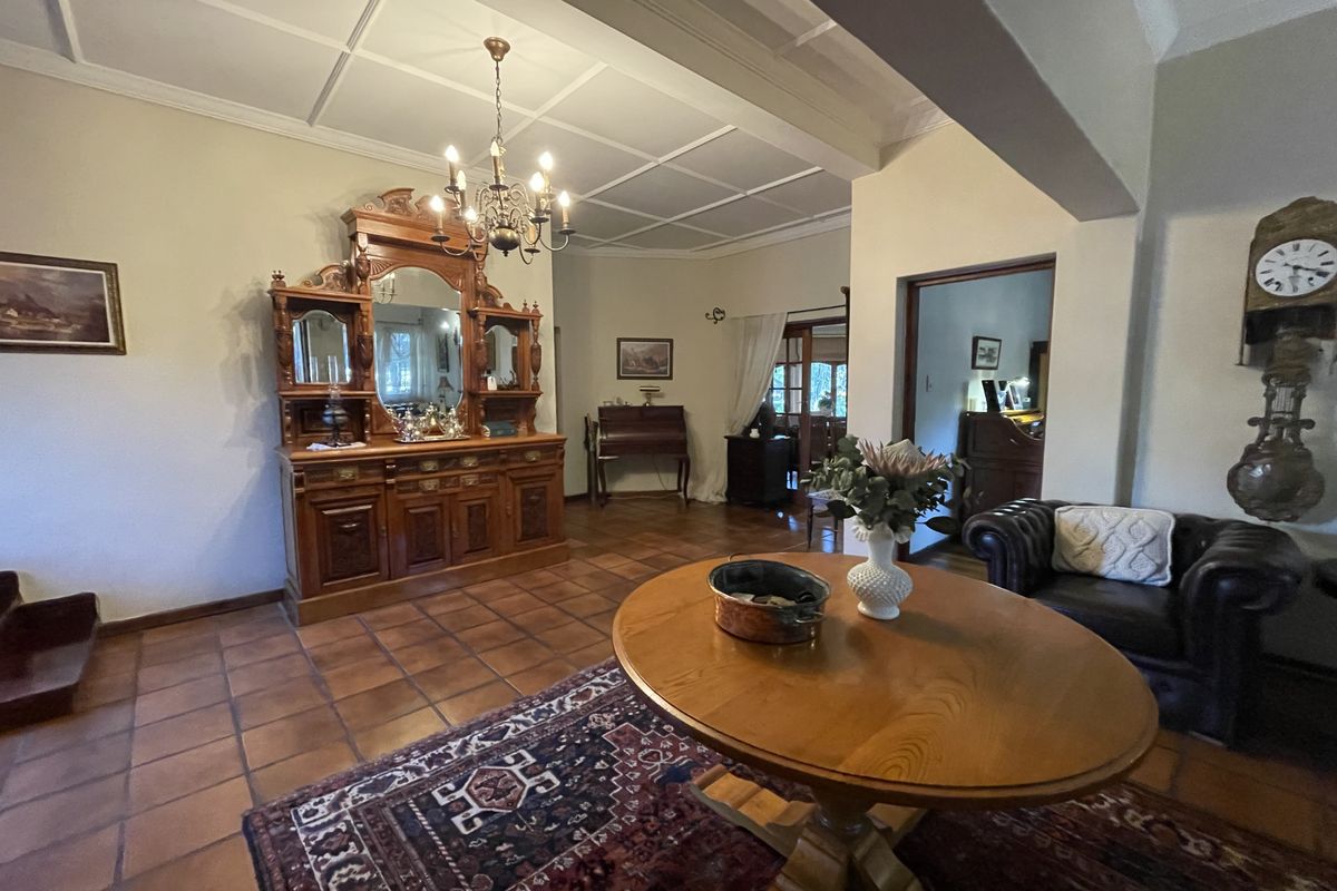 Spacious living area featuring traditional terracotta floor tiles, a classic coffered ceiling, and a central chandelier, offering a warm and character-filled atmosphere.