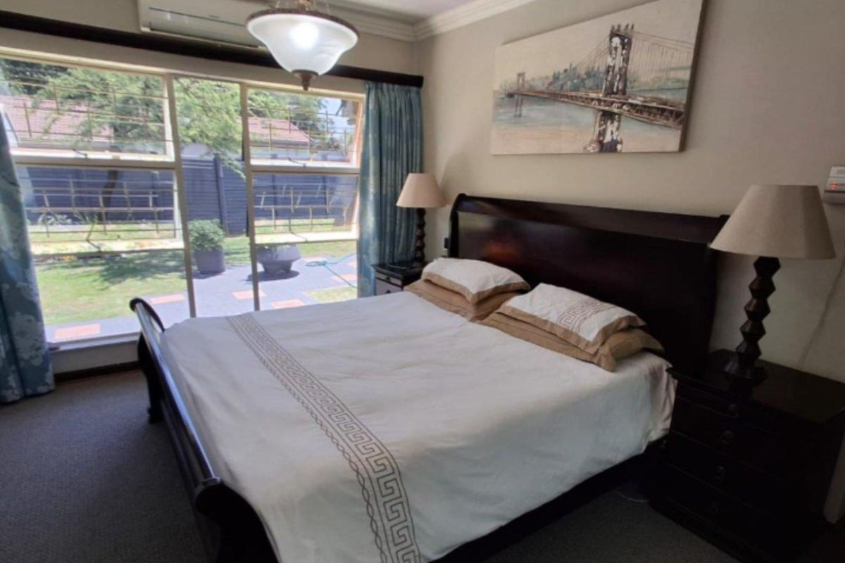 A well-lit bedroom featuring large sliding glass doors that provide direct access to the rear patio and garden area.