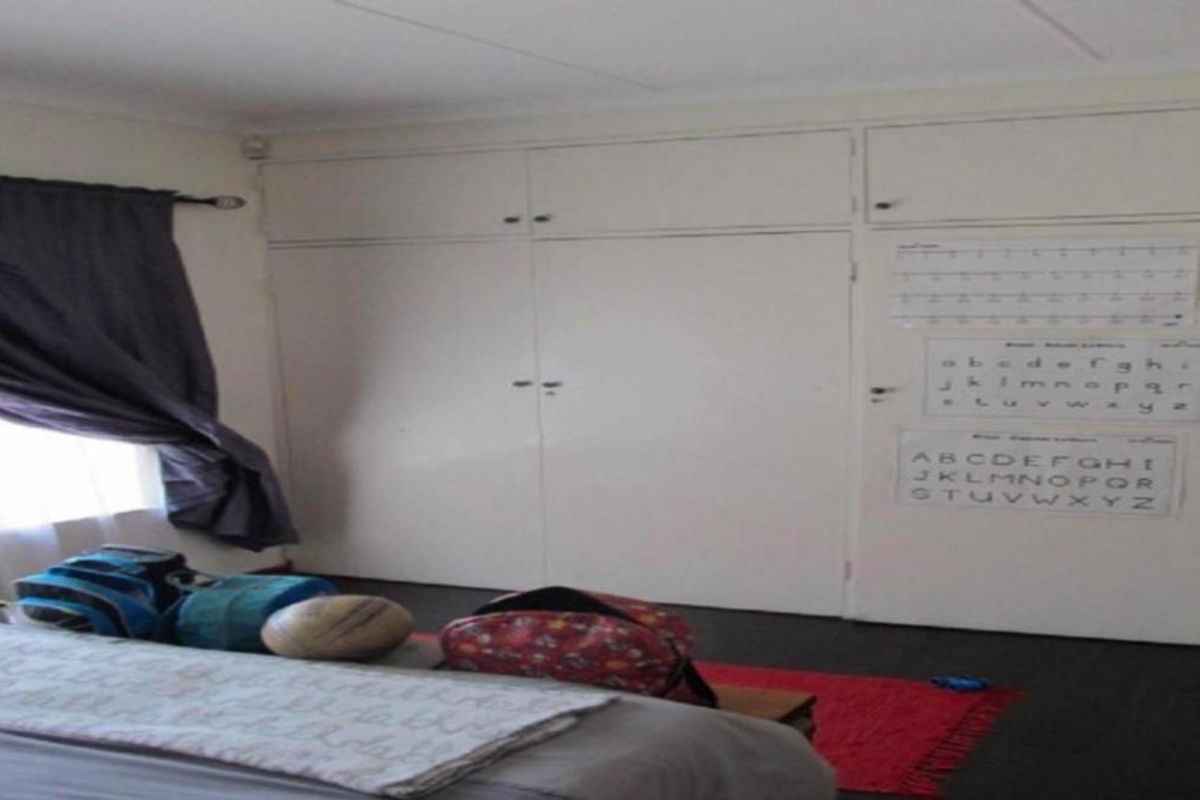 Bedroom featuring built-in floor-to-ceiling cabinetry with overhead storage compartments.