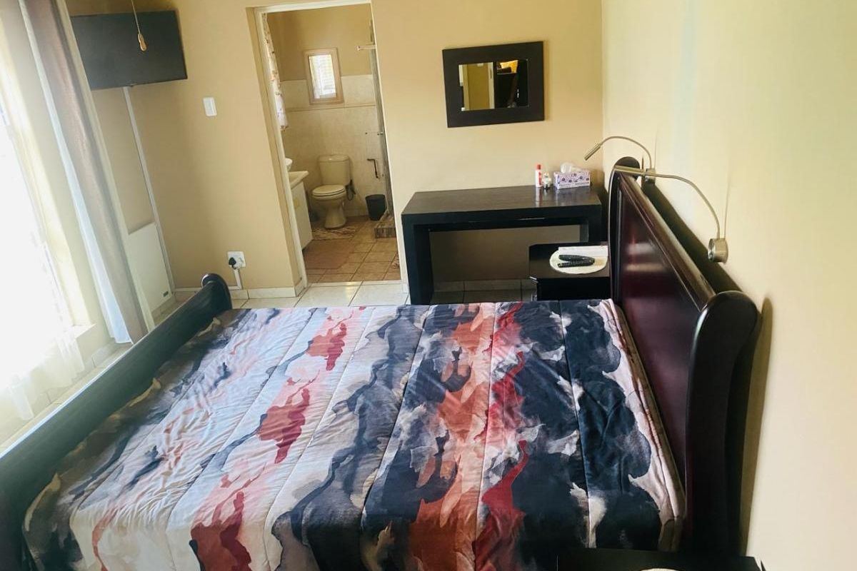 A bedroom featuring tiled flooring and an en-suite bathroom with a toilet and vanity.