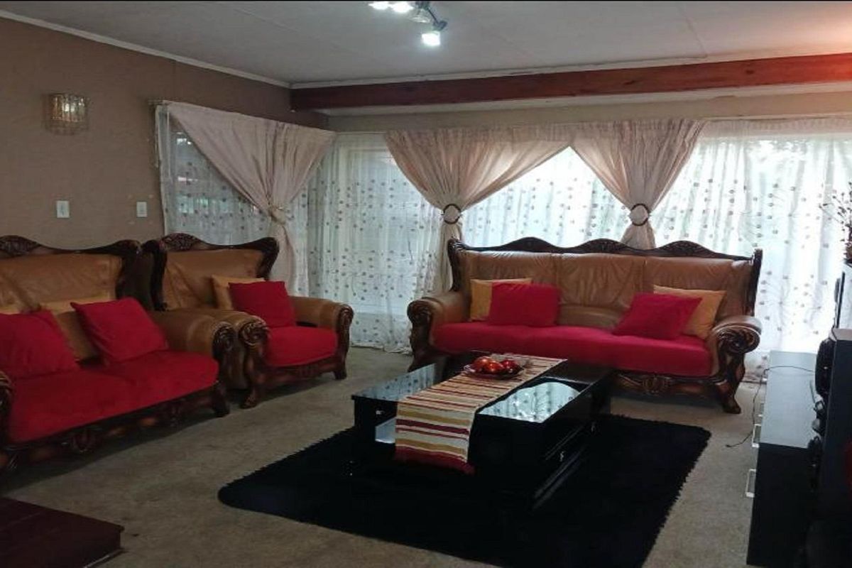 A spacious living room featuring large windows with sheer curtains, providing ample natural light and a comfortable layout for family relaxation.