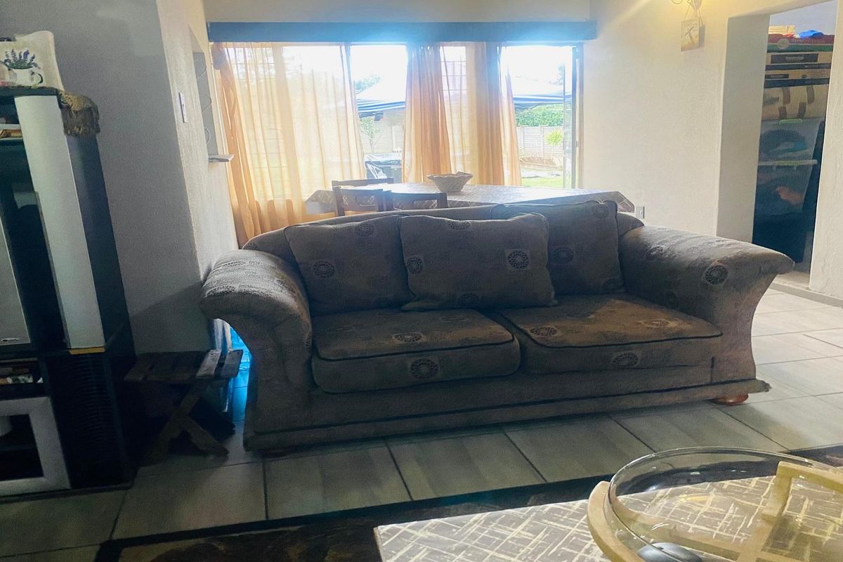 A living room area featuring tiled flooring and large sliding glass doors that provide natural light and access to the outdoor space.