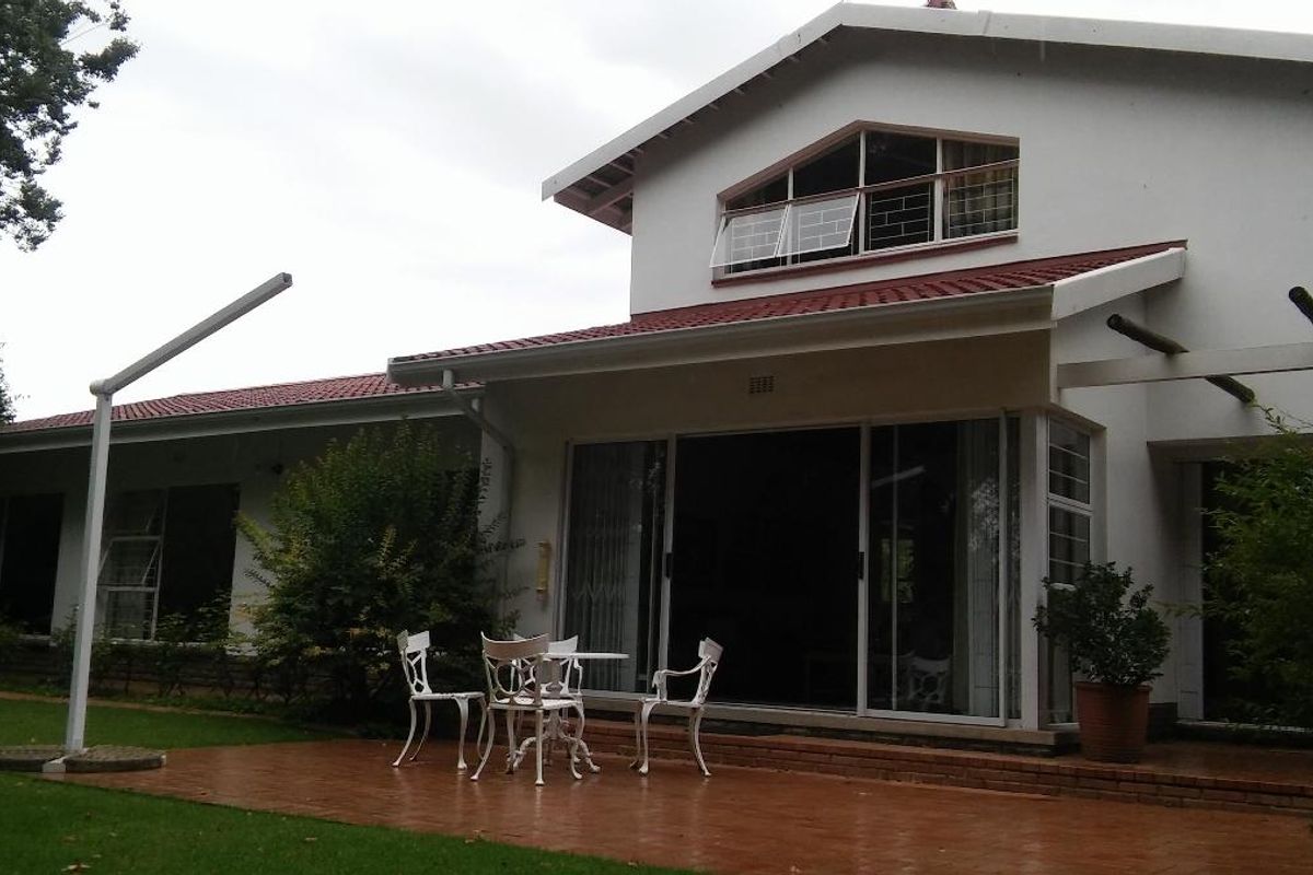 Rear view of the house featuring a paved patio area, sliding glass doors, and a gabled roof design with terracotta tiles.
