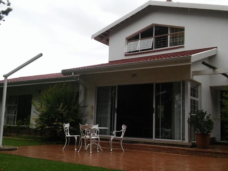 Rear view of the house featuring a paved patio area, sliding glass doors, and a gabled roof design with terracotta tiles.