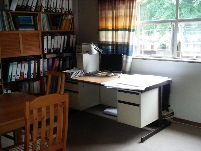 A functional home office space featuring built-in shelving units and a large window providing natural light.
