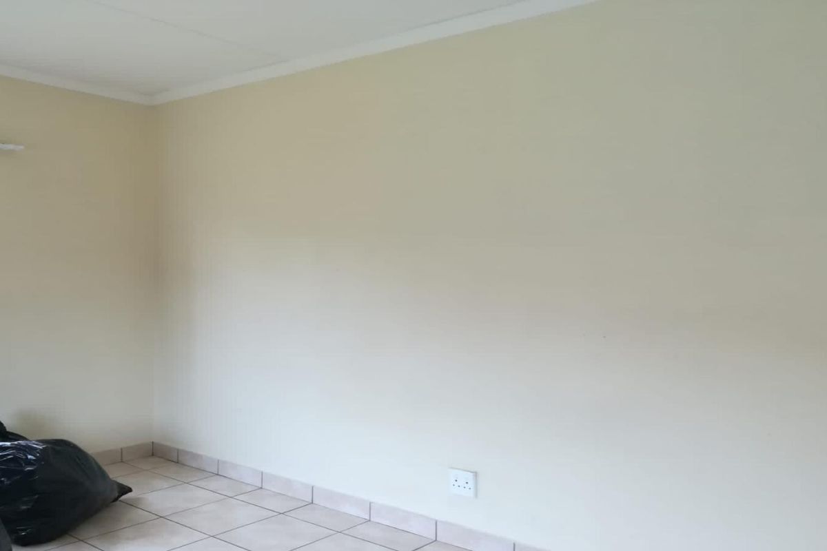 A simple, neutral-toned room featuring tiled flooring and a window, providing a clean and versatile space ready for personalization.