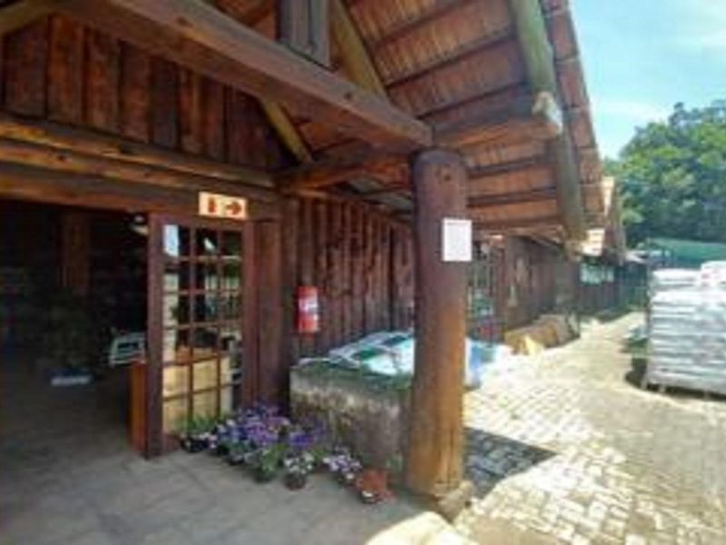 A rustic timber log building exterior featuring exposed wooden beams, a pitched roof, and a paved entrance area.
