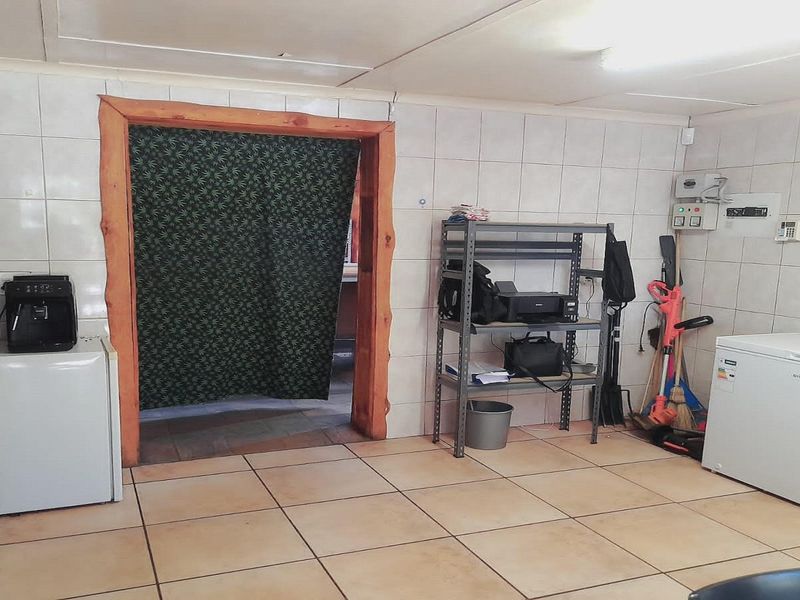 A functional utility space featuring tiled walls and flooring, suitable for storage or laundry use, with a timber-framed doorway leading to an adjacent room.