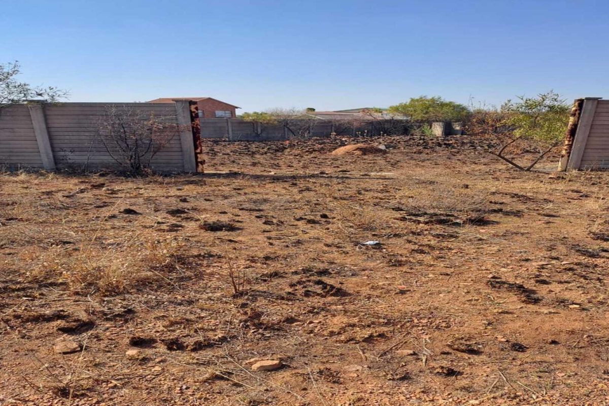 Vacant residential land featuring a partially enclosed perimeter wall and natural terrain, offering a blank canvas for future development.
