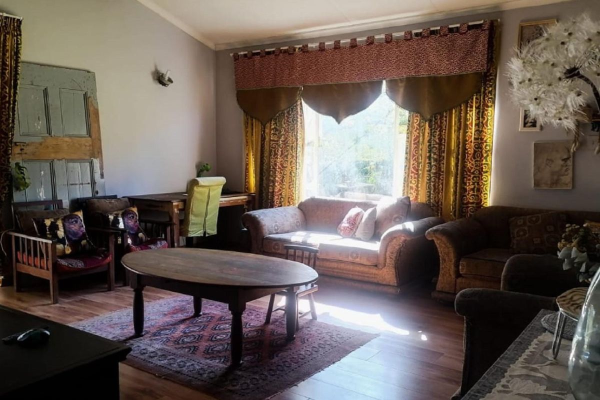 A cozy living room featuring wood-look flooring, a large window allowing natural light, and a vaulted ceiling.