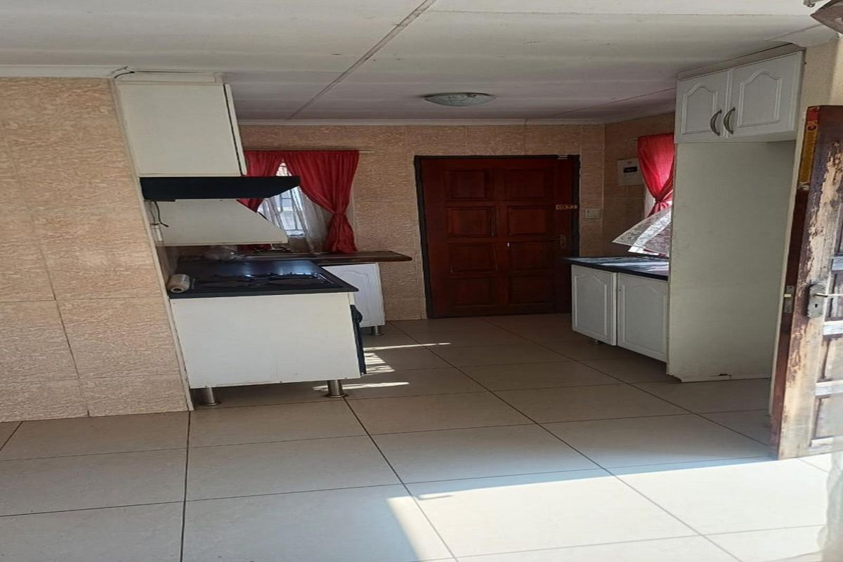 A functional kitchen area featuring built-in cabinetry, a stove with an extractor fan, and tiled flooring, providing a practical layout for daily use.