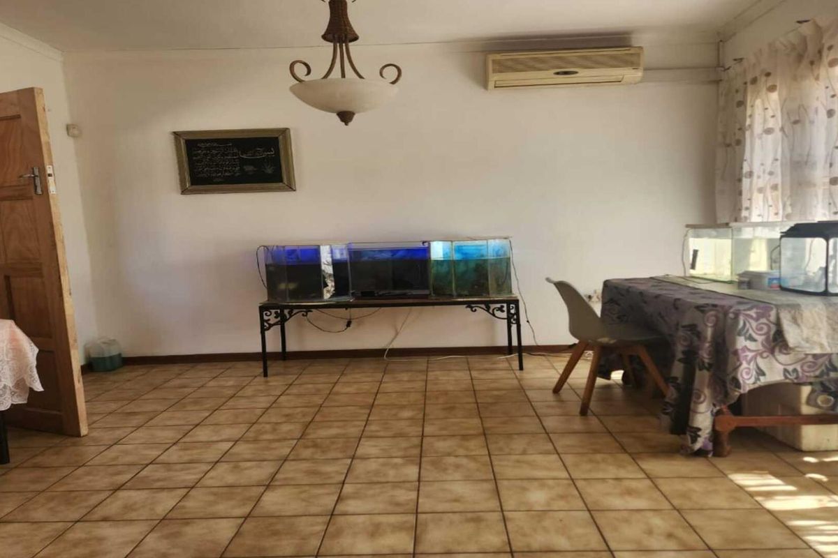A living area featuring tiled flooring, a wall-mounted air conditioning unit, and a central light fixture.