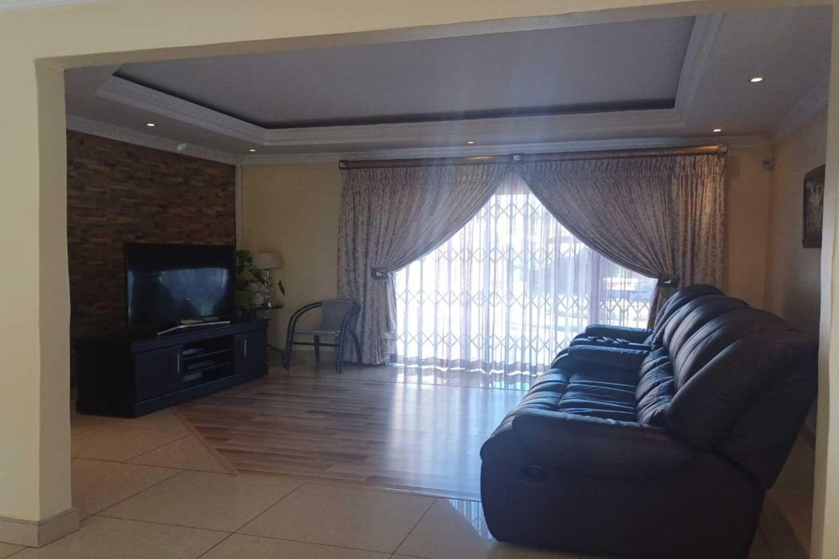 Spacious living room featuring a decorative stone feature wall, recessed ceiling lighting, and large sliding doors leading to the outdoor area.