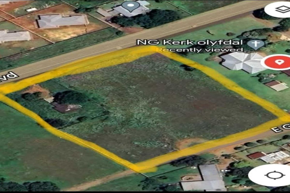 Aerial view of a vacant residential plot highlighted in yellow, situated on a corner lot with road access.