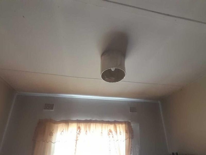 A sparsely furnished bedroom featuring a ceiling with visible signs of wear and discoloration, requiring cosmetic attention.