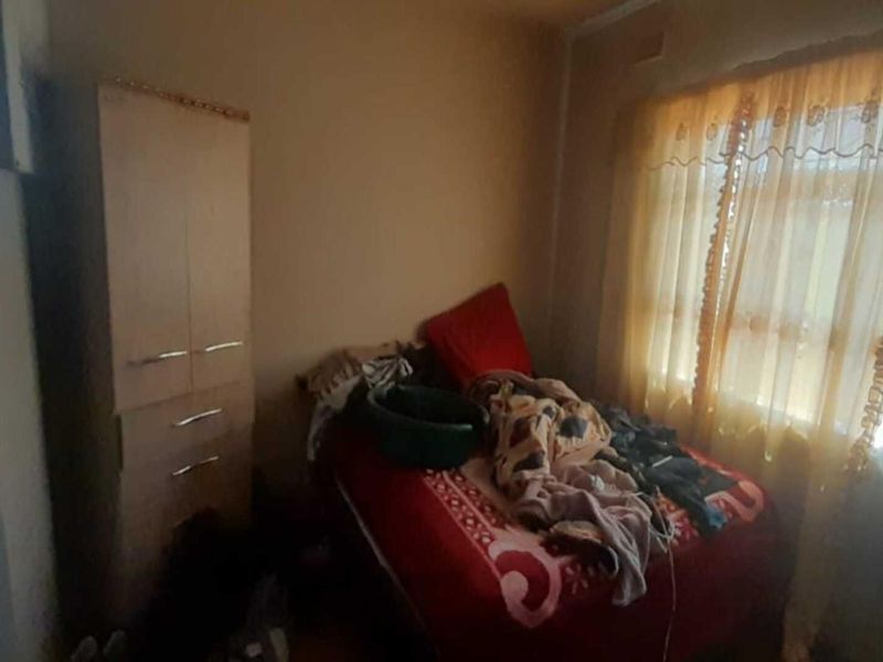 A bedroom featuring a built-in cupboard and natural light from a large window.