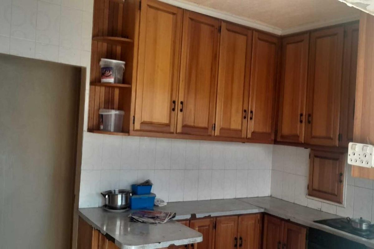 A dated kitchen featuring traditional wooden cabinetry, tiled backsplash, and laminate countertops, offering significant potential for a modern renovation.