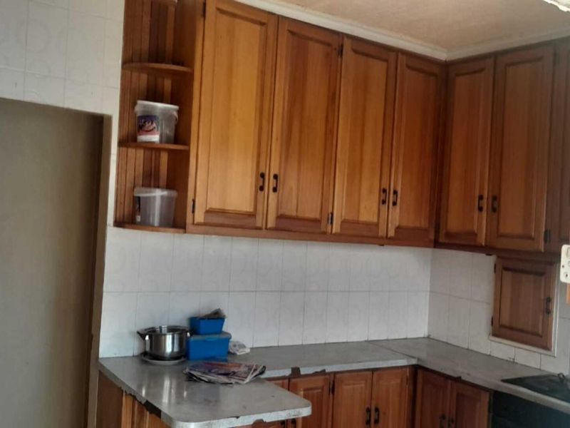 A dated kitchen featuring traditional wooden cabinetry, tiled backsplash, and laminate countertops, offering significant potential for a modern renovation.