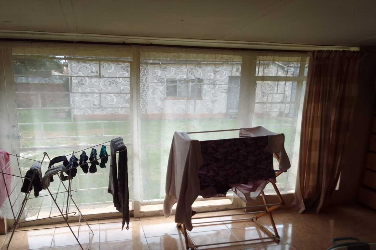 A living area featuring large floor-to-ceiling windows that provide natural light and a view of the rear garden.