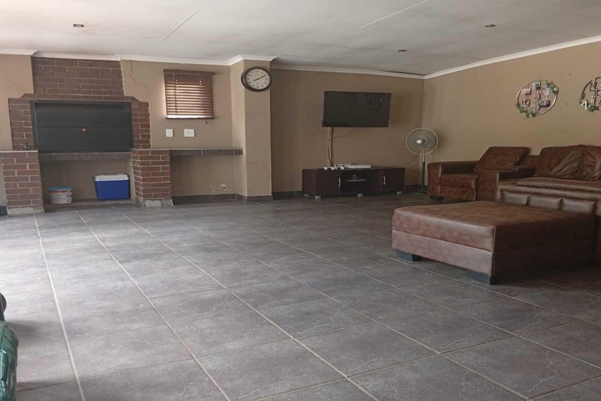 Spacious living area featuring tiled flooring and a built-in brick fireplace, offering a functional and open layout.
