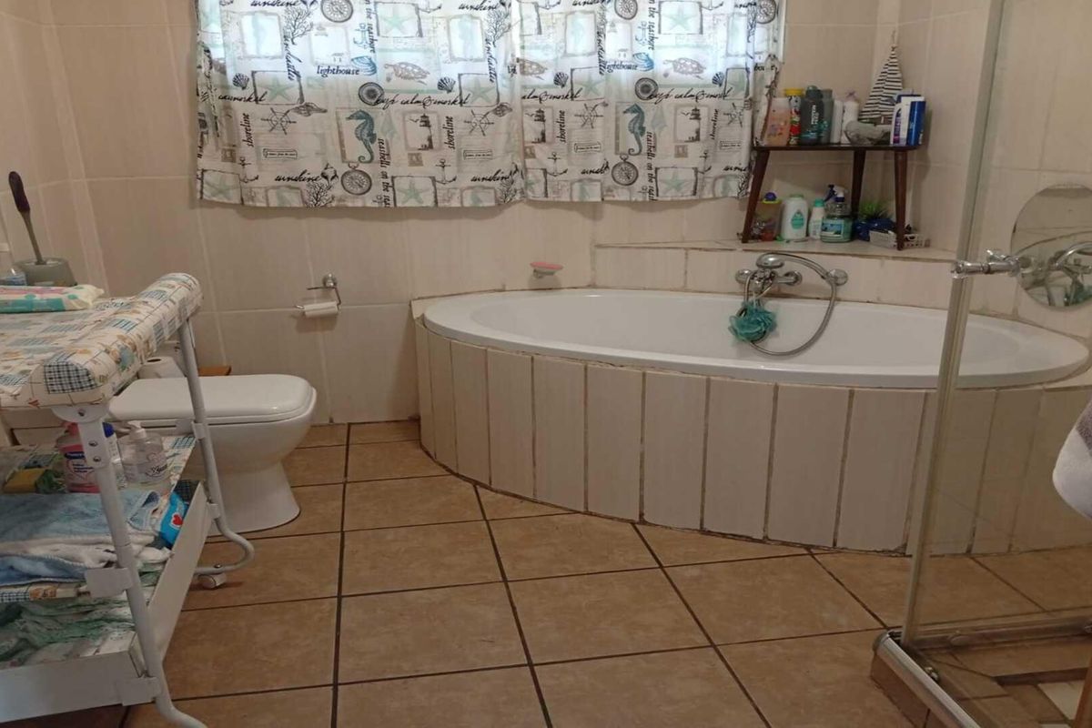 A functional bathroom featuring a built-in corner bathtub, tiled flooring, and wall-mounted fixtures, offering a practical layout for daily use.