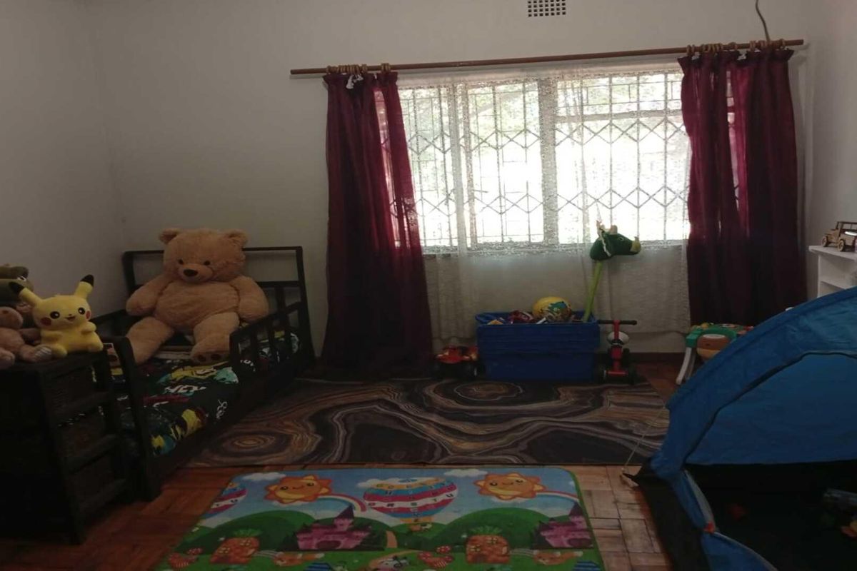 A bedroom featuring parquet flooring, security bars on the window, and curtain rods.