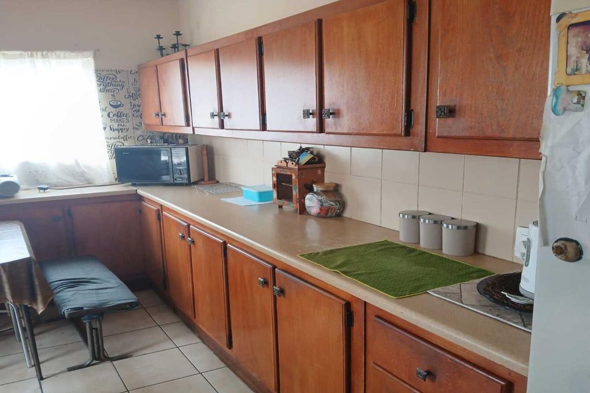 A functional kitchen featuring extensive wooden cabinetry, tiled splashbacks, and tiled flooring, offering a classic layout with ample storage space.