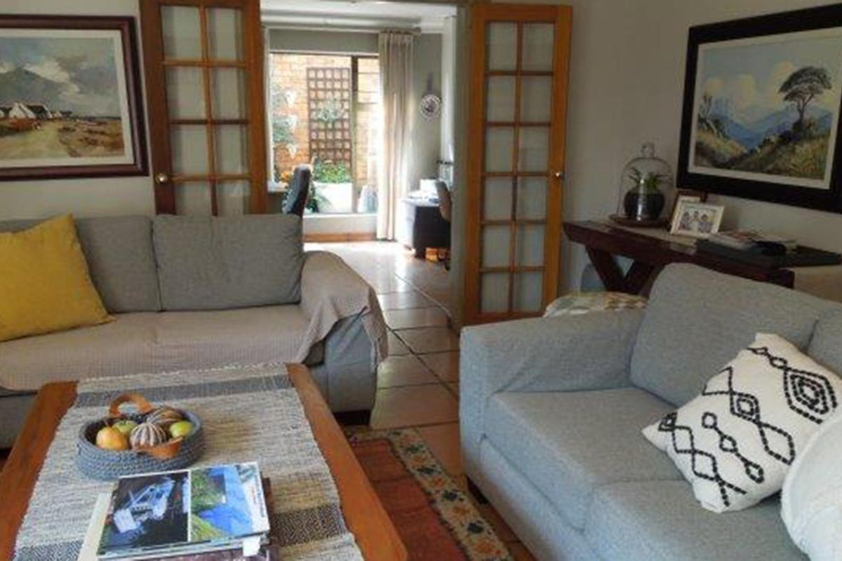 A comfortable living room featuring tiled flooring and classic French doors that provide access to an adjoining space.