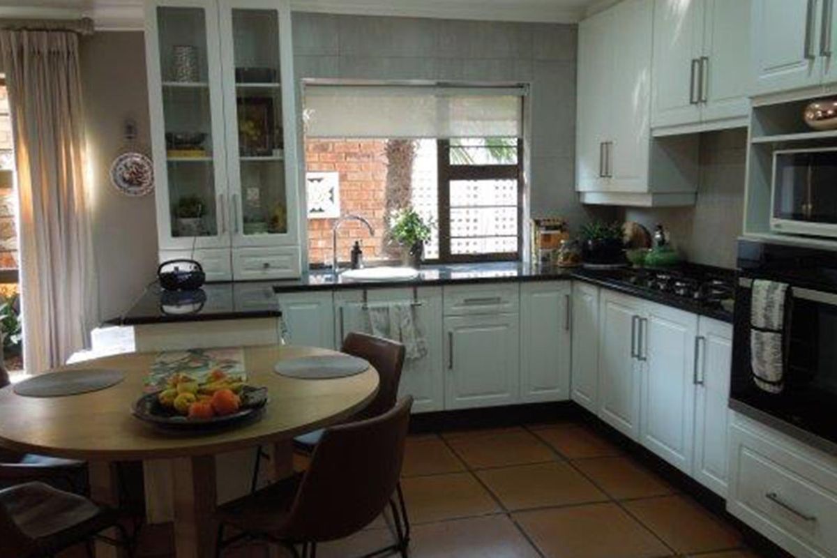 A functional kitchen featuring white cabinetry, dark granite countertops, a built-in oven, and tiled flooring, with direct access to an outdoor area.