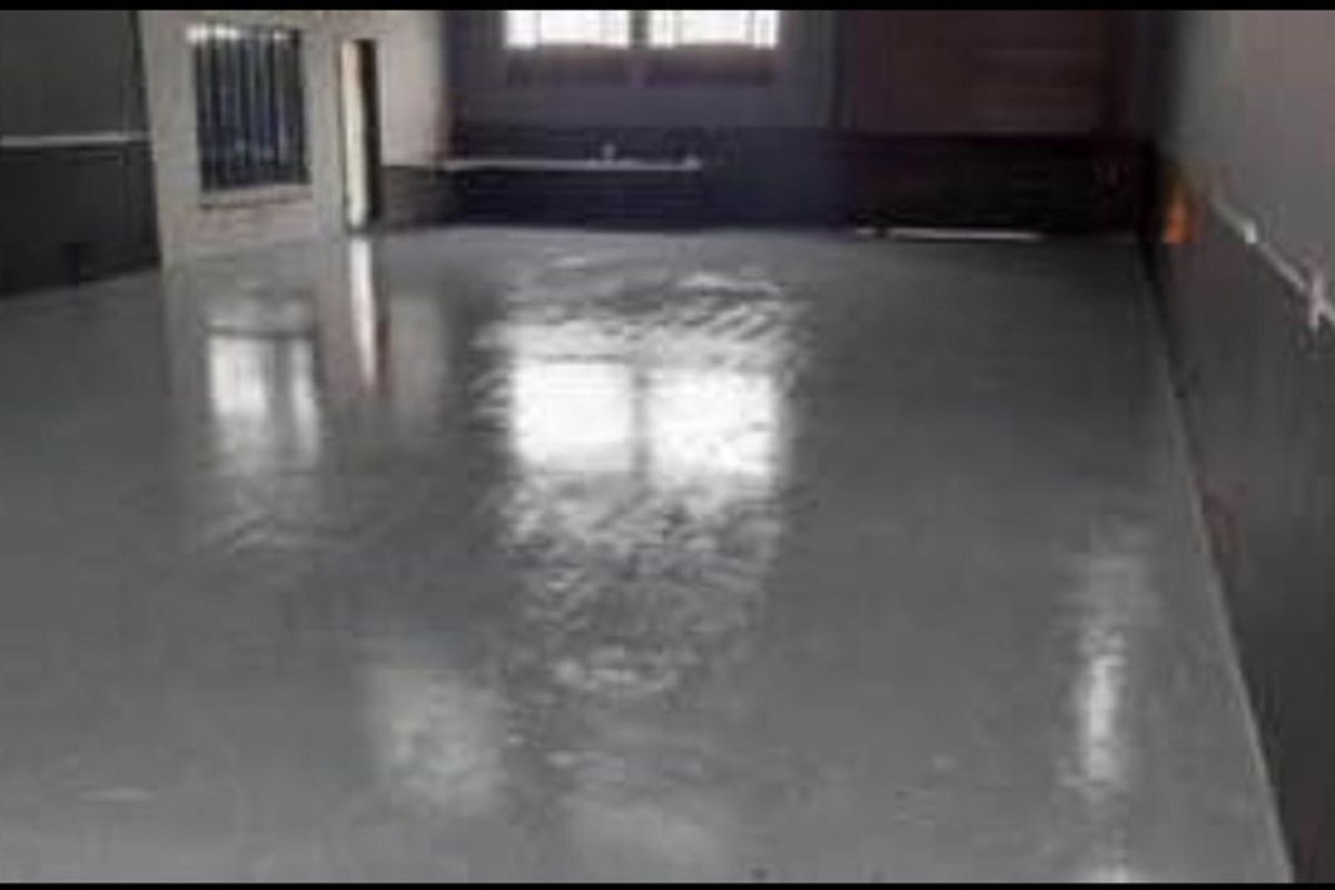 A spacious, empty interior room featuring polished concrete flooring and dark-painted walls, suitable for a variety of uses.
