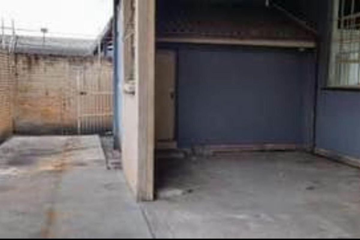 A rear exterior area featuring a concrete patio space, brick boundary wall, and access to the main building structure.