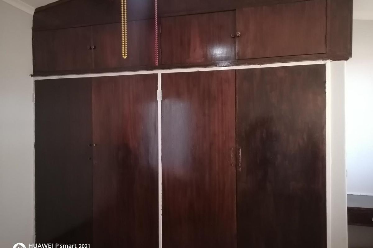 A bedroom featuring floor-to-ceiling built-in wooden cupboards with overhead storage compartments.