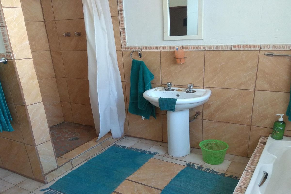 A functional bathroom featuring a pedestal basin, a shower enclosure with a curtain, and a bathtub with tiled wall finishes.
