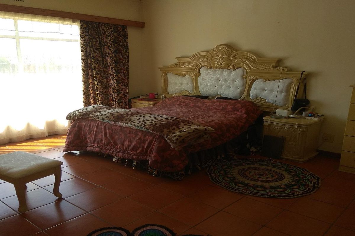 A spacious bedroom featuring large windows with natural light, tiled flooring, and neutral wall finishes.