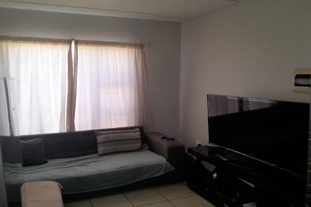 A living room area featuring tiled flooring and a window with curtain tracks.